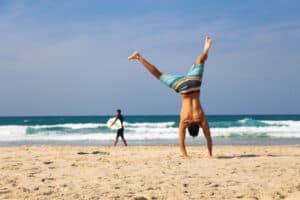 Jugendlicher macht ein Radschlag am Strand