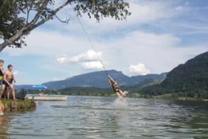 Kind schwingt am Seil ins Wasser
